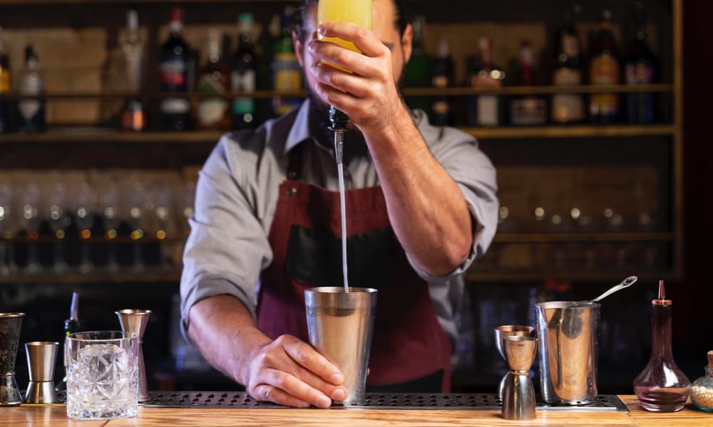 barman qui fait un cocktail pour ses clients